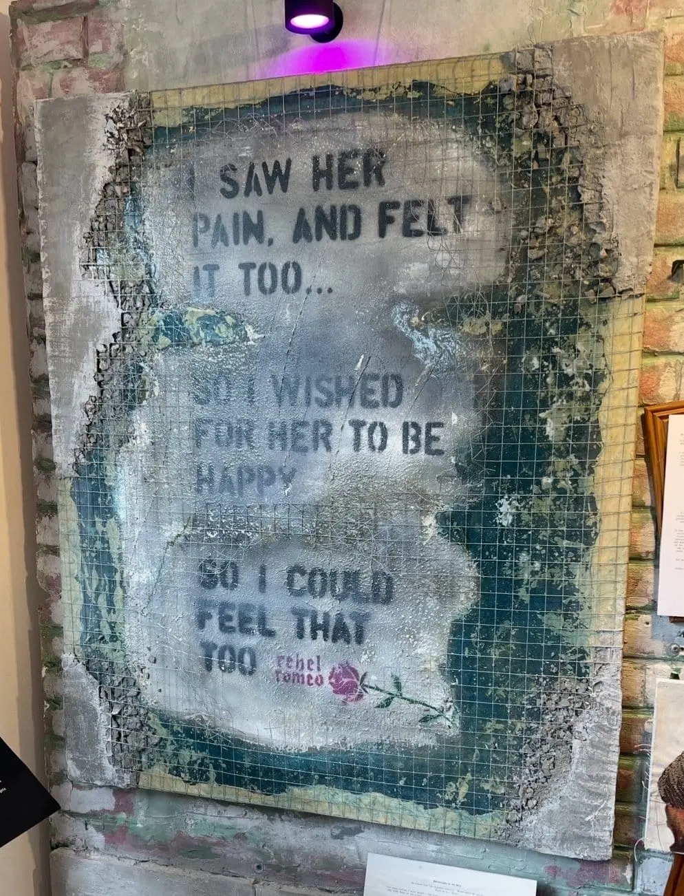 Reflections in the Rain canvas hung on exposed brick under violet gallery light
